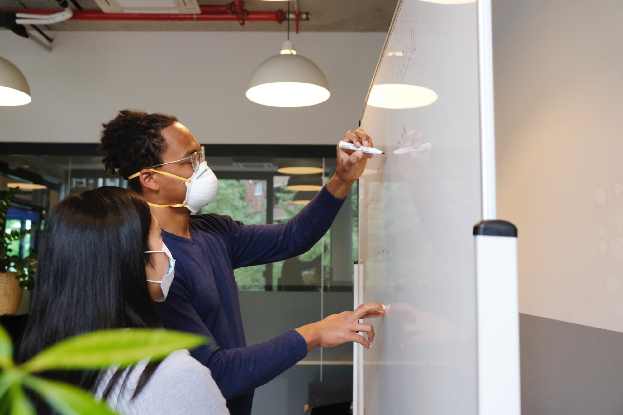 person wearing mask and writing on white board